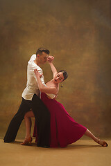 Image showing Dance ballroom couple in gold dress dancing on studio background.