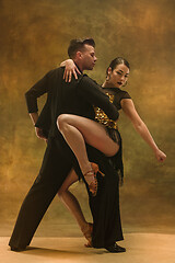 Image showing Dance ballroom couple in gold dress dancing on studio background.