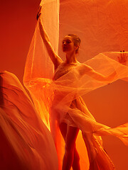 Image showing Ballerina. Young graceful female ballet dancer dancing over red studio. Beauty of classic ballet.