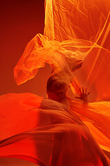 Image showing Ballerina. Young graceful female ballet dancer dancing over red studio. Beauty of classic ballet.