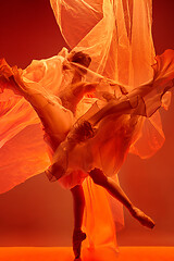 Image showing Ballerina. Young graceful female ballet dancer dancing over red studio. Beauty of classic ballet.