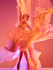 Image showing Ballerina. Young graceful female ballet dancer dancing over red studio. Beauty of classic ballet.