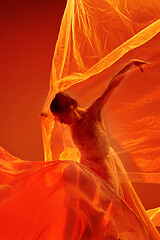 Image showing Ballerina. Young graceful female ballet dancer dancing over red studio. Beauty of classic ballet.