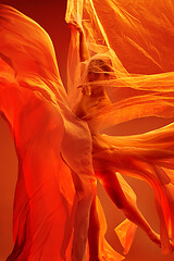 Image showing Ballerina. Young graceful female ballet dancer dancing over red studio. Beauty of classic ballet.