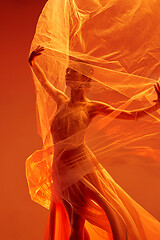 Image showing Ballerina. Young graceful female ballet dancer dancing over red studio. Beauty of classic ballet.