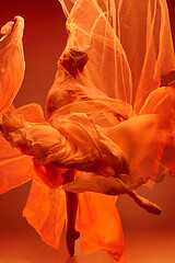 Image showing Ballerina. Young graceful female ballet dancer dancing over red studio. Beauty of classic ballet.