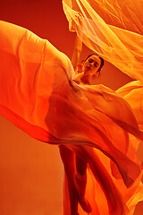 Image showing Ballerina. Young graceful female ballet dancer dancing over red studio. Beauty of classic ballet.