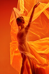 Image showing Ballerina. Young graceful female ballet dancer dancing over red studio. Beauty of classic ballet.