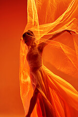 Image showing Ballerina. Young graceful female ballet dancer dancing over red studio. Beauty of classic ballet.