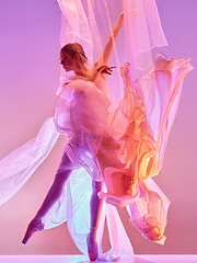 Image showing Ballerina. Young graceful female ballet dancer dancing over pink studio. Beauty of classic ballet.