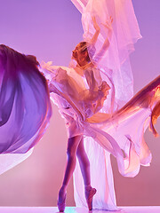 Image showing Ballerina. Young graceful female ballet dancer dancing over pink studio. Beauty of classic ballet.