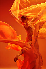 Image showing Ballerina. Young graceful female ballet dancer dancing over red studio. Beauty of classic ballet.