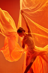 Image showing Ballerina. Young graceful female ballet dancer dancing over red studio. Beauty of classic ballet.