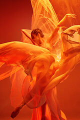 Image showing Ballerina. Young graceful female ballet dancer dancing over red studio. Beauty of classic ballet.