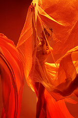 Image showing Ballerina. Young graceful female ballet dancer dancing over red studio. Beauty of classic ballet.