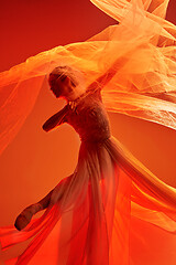 Image showing Ballerina. Young graceful female ballet dancer dancing over red studio. Beauty of classic ballet.