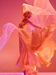 Image showing Ballerina. Young graceful female ballet dancer dancing over red studio. Beauty of classic ballet.