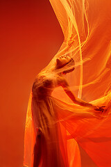 Image showing Ballerina. Young graceful female ballet dancer dancing over red studio. Beauty of classic ballet.