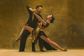 Image showing Dance ballroom couple in gold dress dancing on studio background.