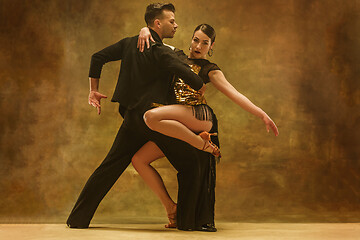 Image showing Dance ballroom couple in gold dress dancing on studio background.