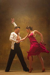 Image showing Dance ballroom couple in gold dress dancing on studio background.