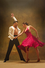 Image showing Dance ballroom couple in gold dress dancing on studio background.