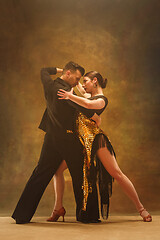 Image showing Dance ballroom couple in gold dress dancing on studio background.