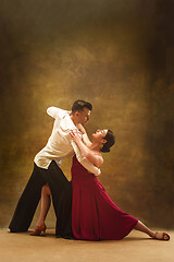 Image showing Dance ballroom couple in gold dress dancing on studio background.