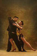 Image showing Dance ballroom couple in gold dress dancing on studio background.