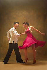 Image showing Dance ballroom couple in gold dress dancing on studio background.