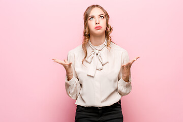 Image showing Beautiful female half-length portrait isolated on pink studio backgroud. The young emotional surprised woman