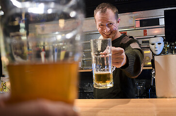 Image showing Bartender cheers with a beer in the bar