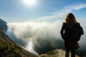 Image showing Girl is watching from the mountain on an unusual seascape with clouds over the sea