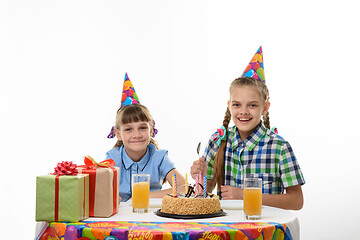 Image showing Two girls at the festive table ready to eat cake