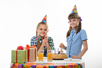 Image showing Two girls put candles in a birthday cake