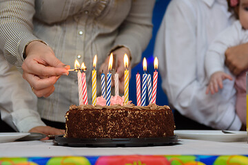 Image showing Mom lights candles on a cake at a birthday party