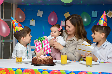 Image showing Two boys congratulate mom, mom holds in her arms a six-month-old baby