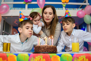 Image showing Family blowing candles on birthday cake