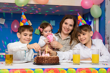 Image showing Children on a family birthday put candles in a birthday cake