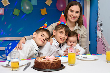 Image showing Happy family hugs mom at birthday party