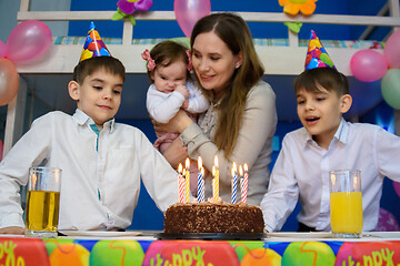 Image showing Children prepare to put out candles on a festive cake