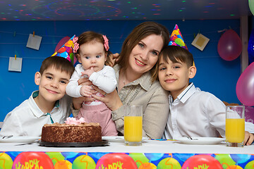 Image showing Mom, two sons and a baby daughter at the festive table in the home interior