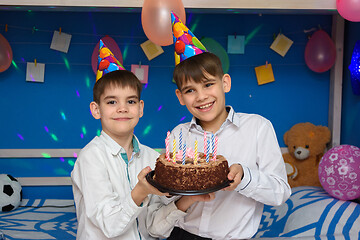 Image showing Two brothers hold a holiday cake at a holiday