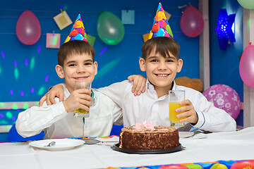 Image showing Two boys eat cake and drink juice at a birthday party