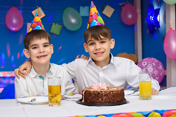 Image showing Two brothers hug each other while sitting at the festive table