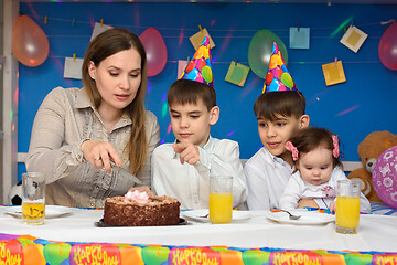 Image showing Mom cuts a birthday cake with her children