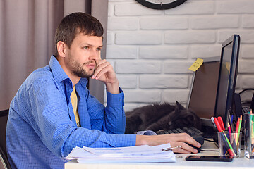 Image showing Freelancer thoughtfully looks out the window, sitting at his workplace