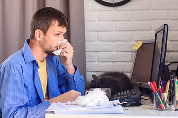 Image showing A sick self-employed person wipes his snotty nose with napkins.