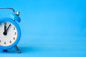 Image showing Part of the alarm clock on the left, on the right is an empty place, blue background