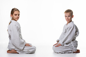 Image showing A girl and a boy in a sports kimono sit opposite each other and looked into the frame